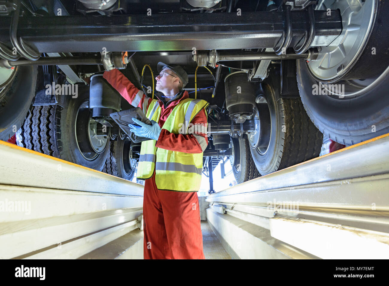 Worker inspecting underside of trailer on production line in trailer factory Stock Photo