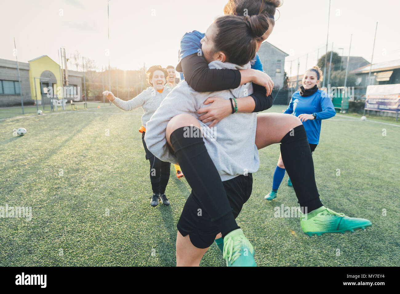 Football players jubilant and hugging on pitch Stock Photo