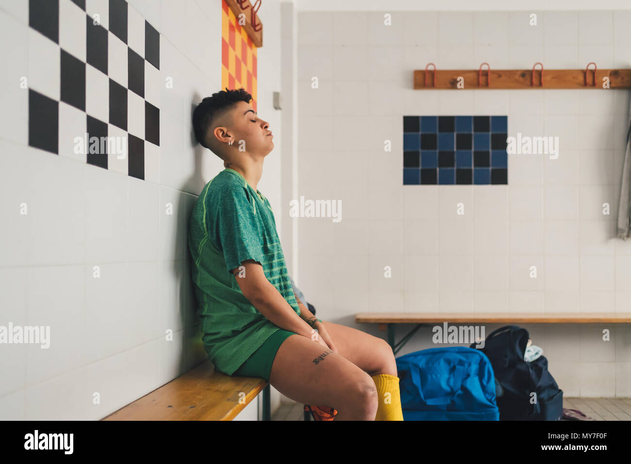 Football player on bench in changing room Stock Photo