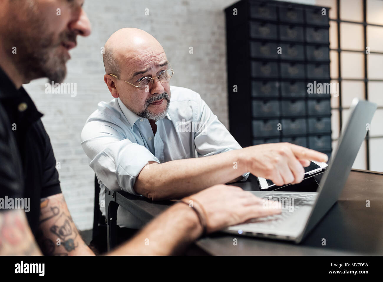 Colleagues looking at laptop together Stock Photo