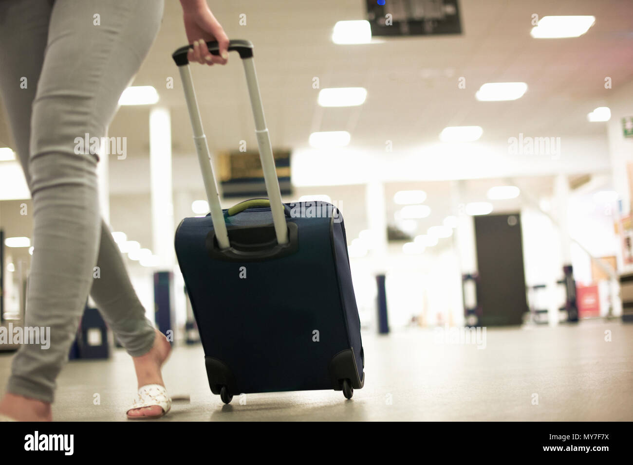 Woman with wheeled suitcase in airport Stock Photo