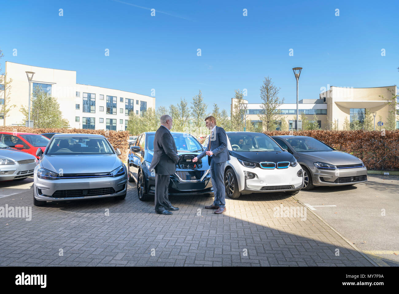 Businessmen looking at range of electric cars in business park Stock Photo