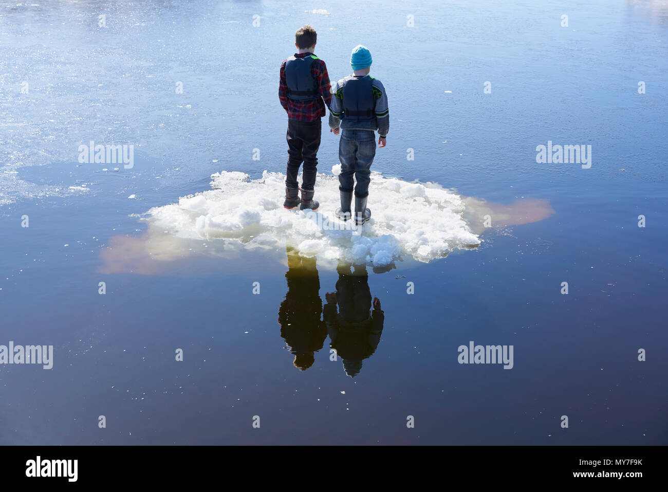 Two boys standing on ice, on lake, rear view Stock Photo
