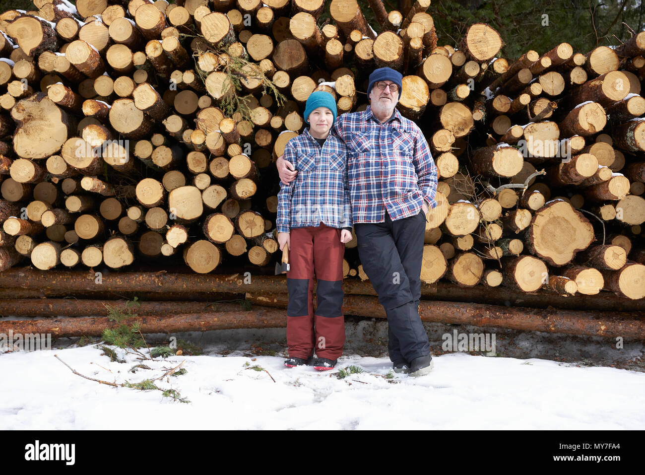 Portrait of father and son, in front of  stack of logs Stock Photo