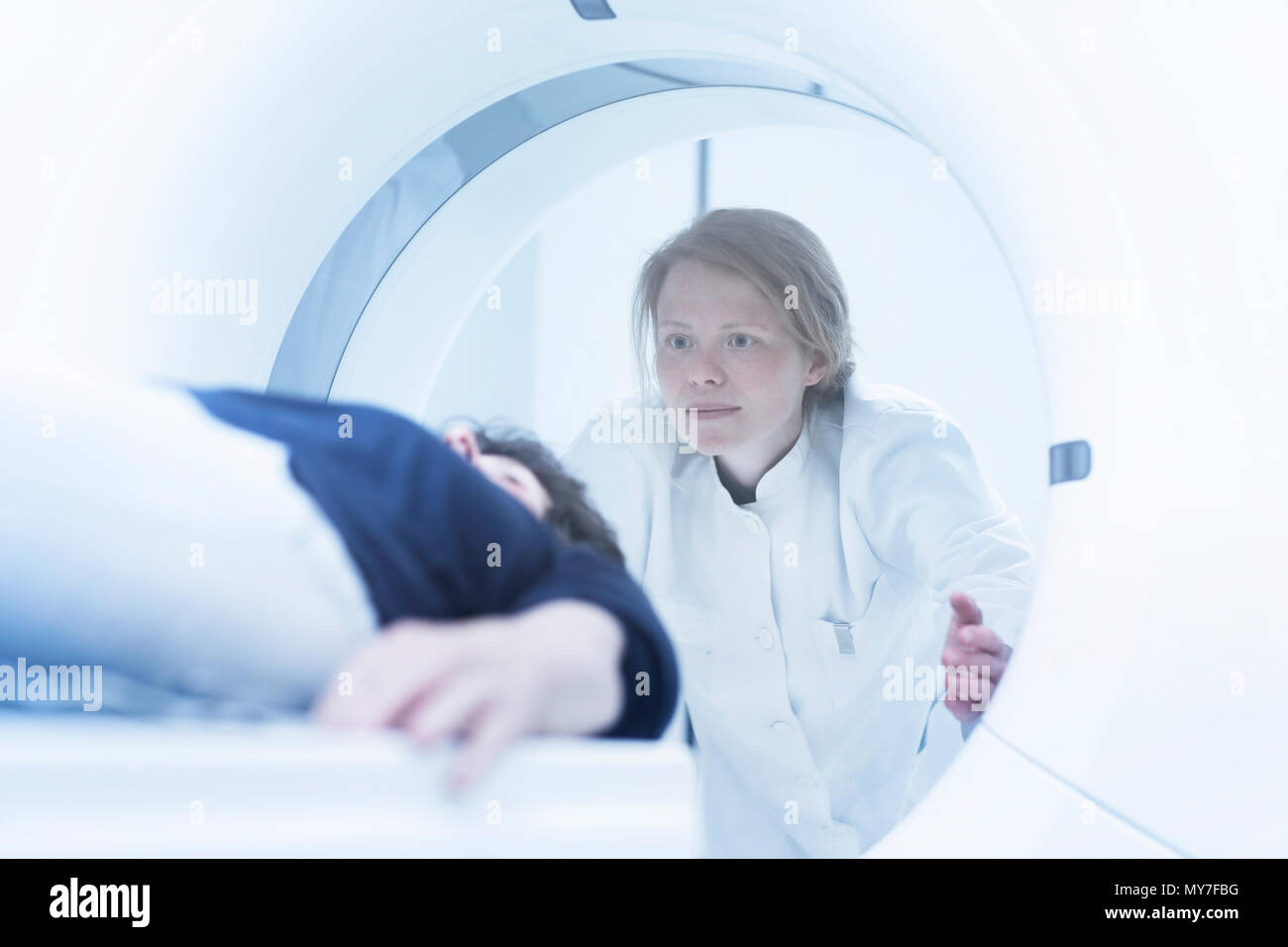 Mature woman having CT scan, radiologist standing beside tunnel Stock Photo