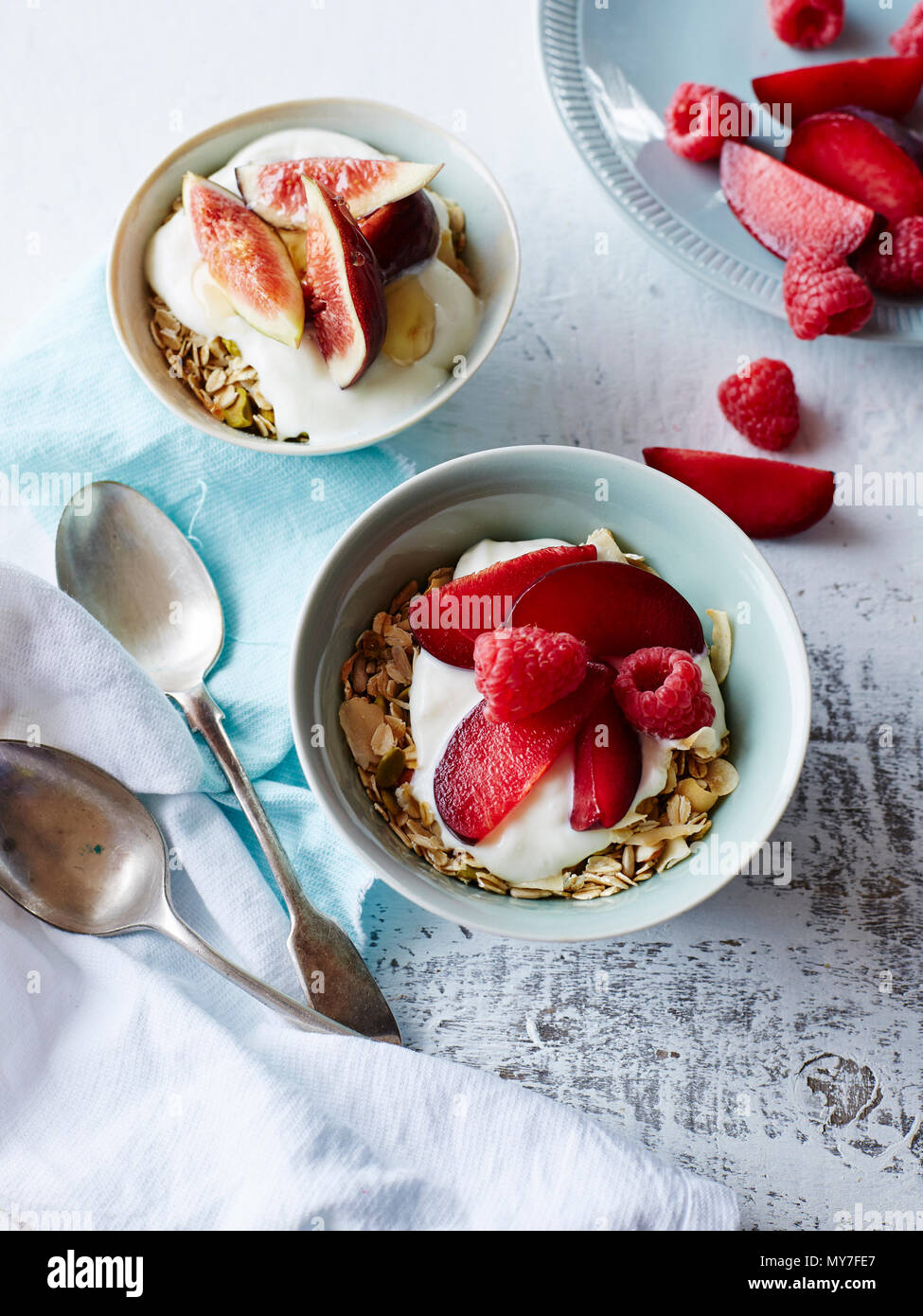 Still life of nut muesli and yogurt in bowls with fresh fruit, overhead view Stock Photo