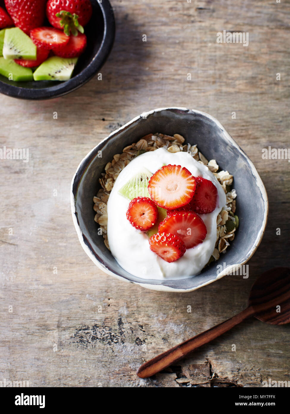 Still life with bowl of fruit and muesli with strawberry kiwi yogurt, overhead view Stock Photo
