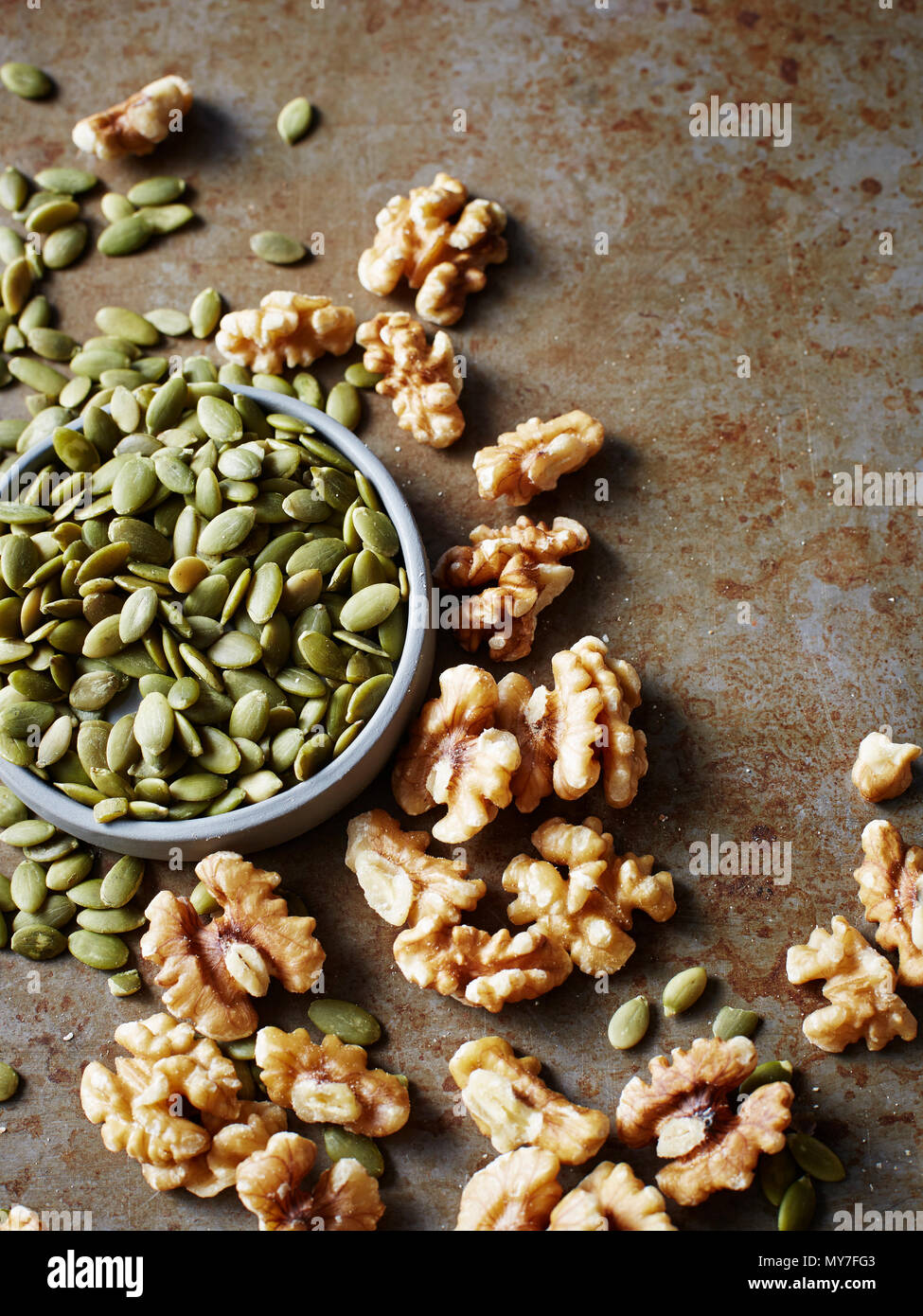 Still life with bowl of pumpkin seeds and walnuts, overhead view Stock Photo