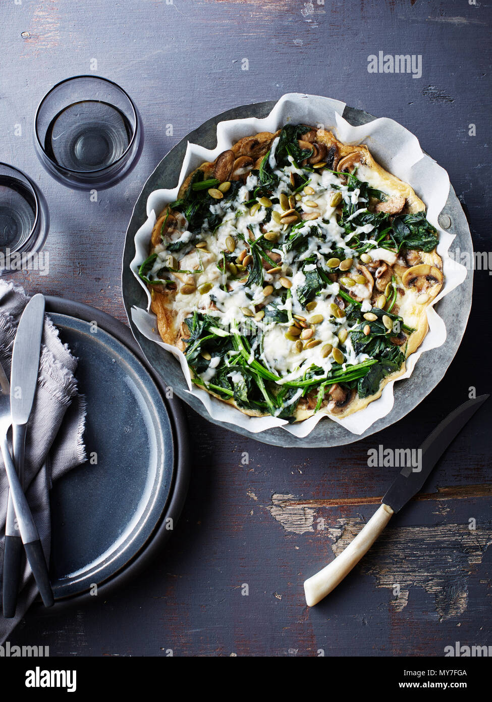 Still life with bowl of spinach feta mushroom frittata, overhead view Stock Photo