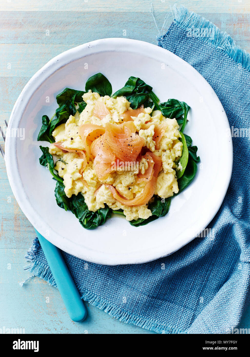 Still life with plate of scrambled eggs and salmon on spinach, overhead view Stock Photo