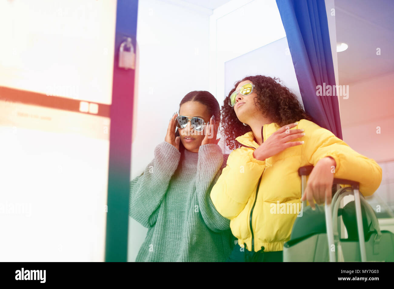 Two mid adult women wearing sunglasses in airport Stock Photo