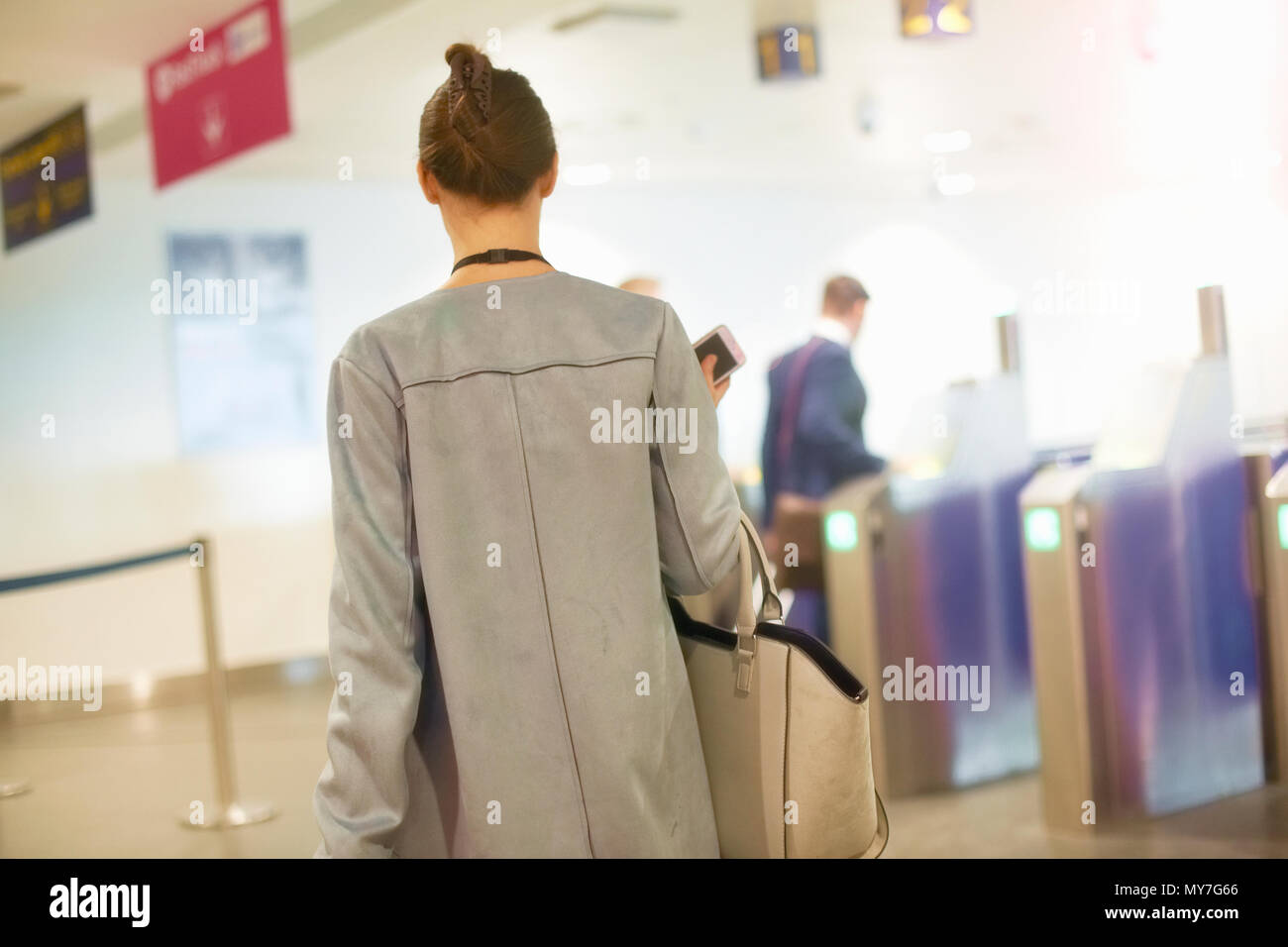 Businessmen and women walking through security gate at airport, rear view Stock Photo