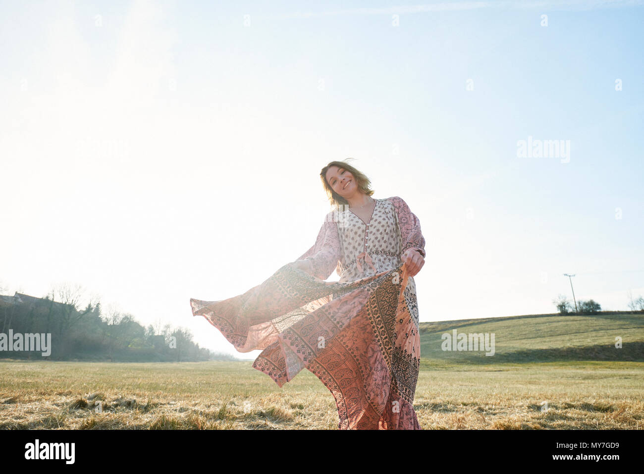 Hippy style woman dancing in sunlit in field, portrait Stock Photo