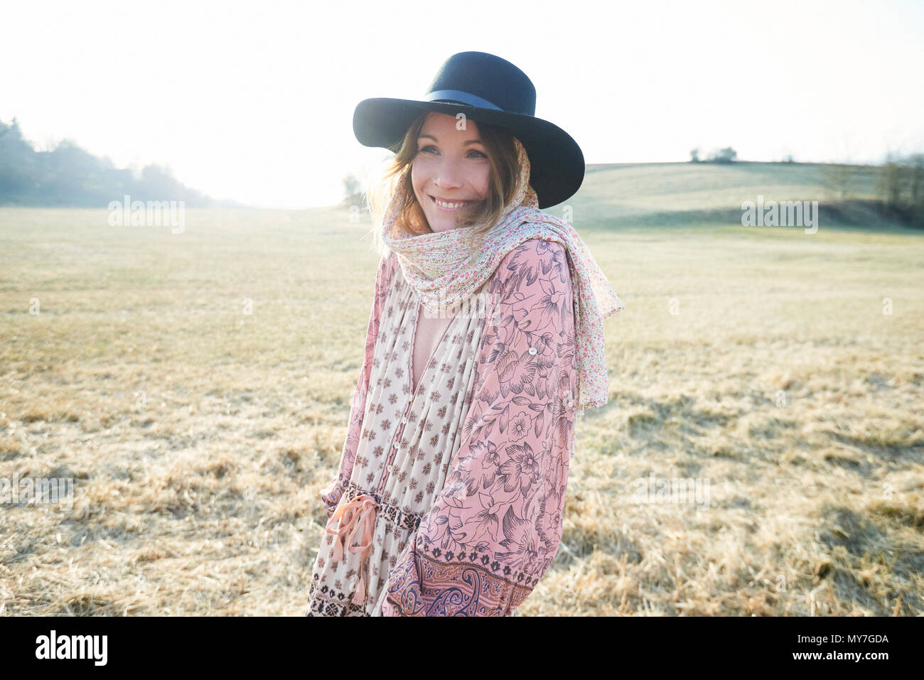 Hippy style woman wearing felt hat in field, portrait Stock Photo