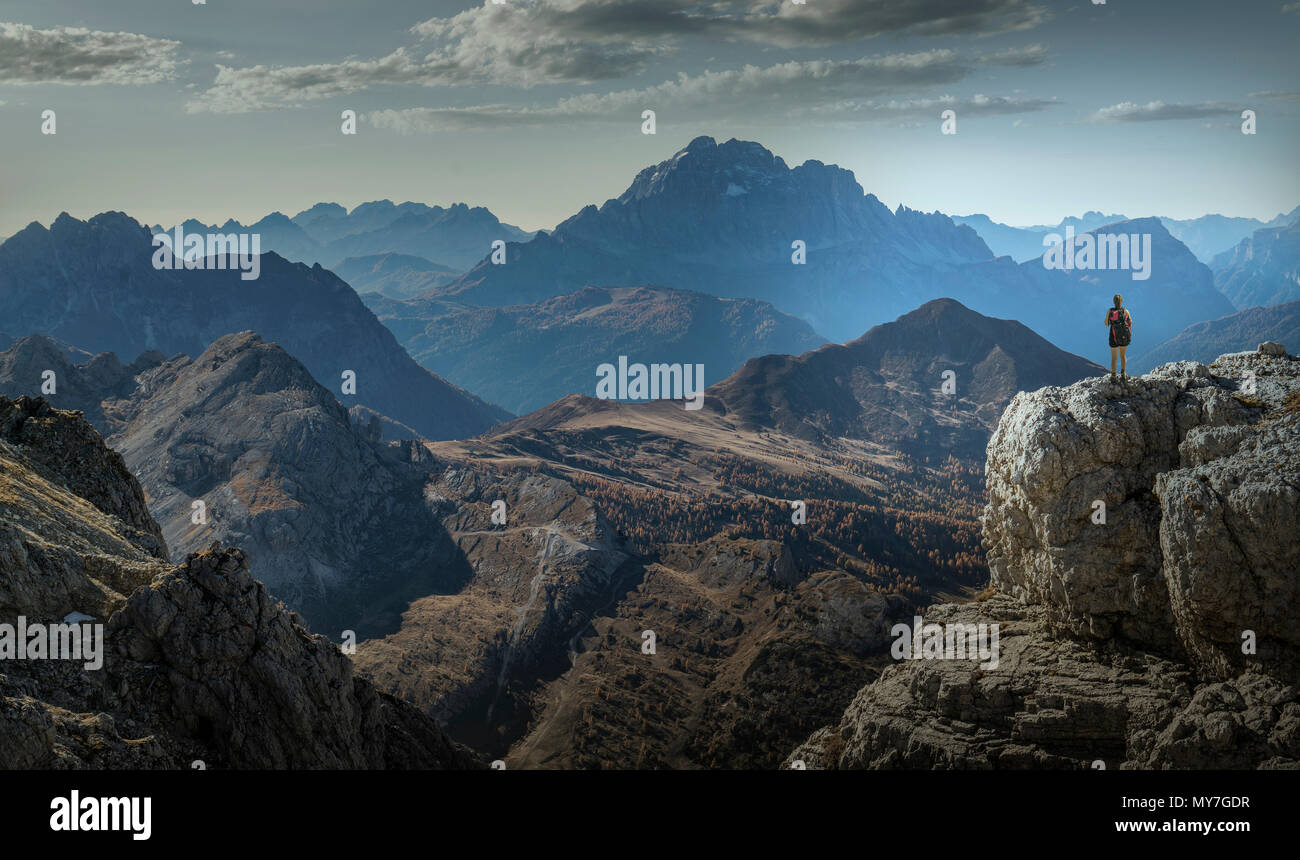 Climber on cliff looking at mountain ranges, Dolomites, Cortina d'Ampezzo, Veneto, Italy Stock Photo