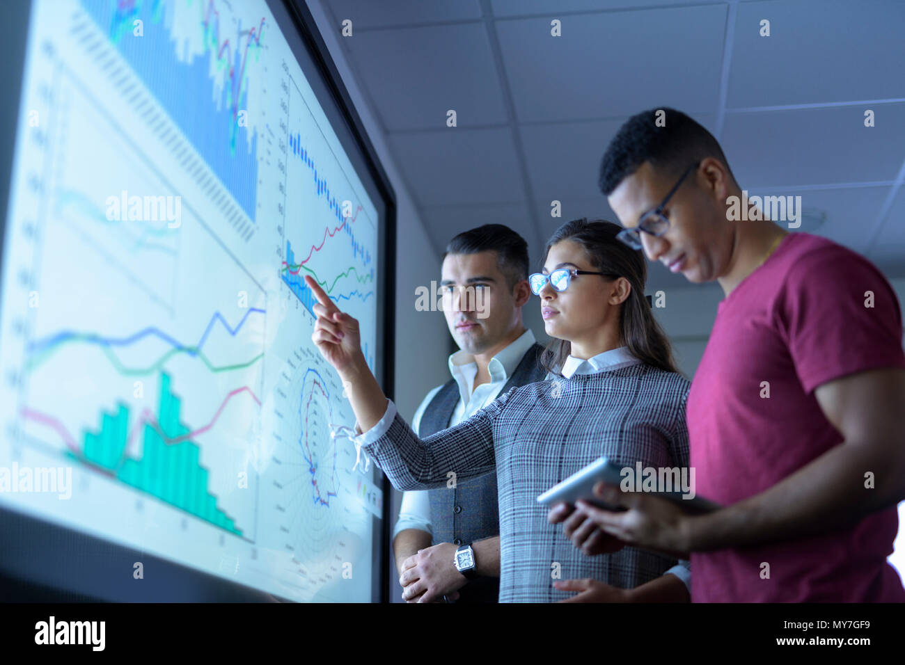 Business team viewing charts and graphs on interactive screen in business meeting Stock Photo