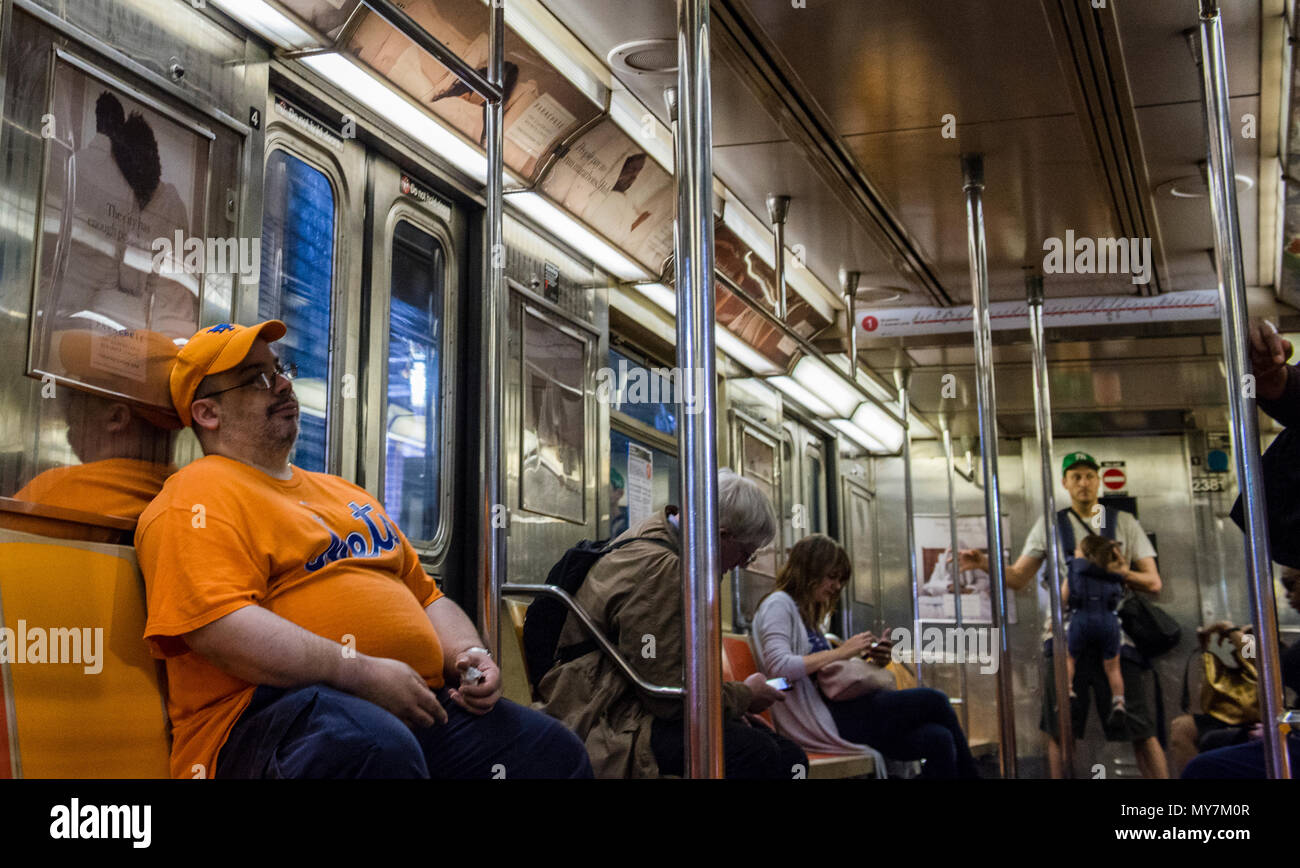 Large man wearing matching Mets orange cap and t-shirt, sitting on New York City subway train, New York City, USA Stock Photo