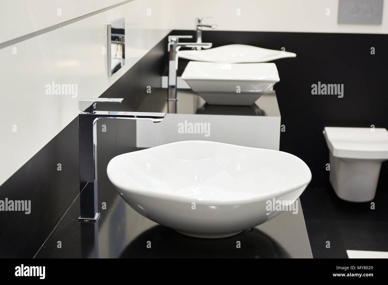 Ceramic sink with faucets in public toilet Stock Photo