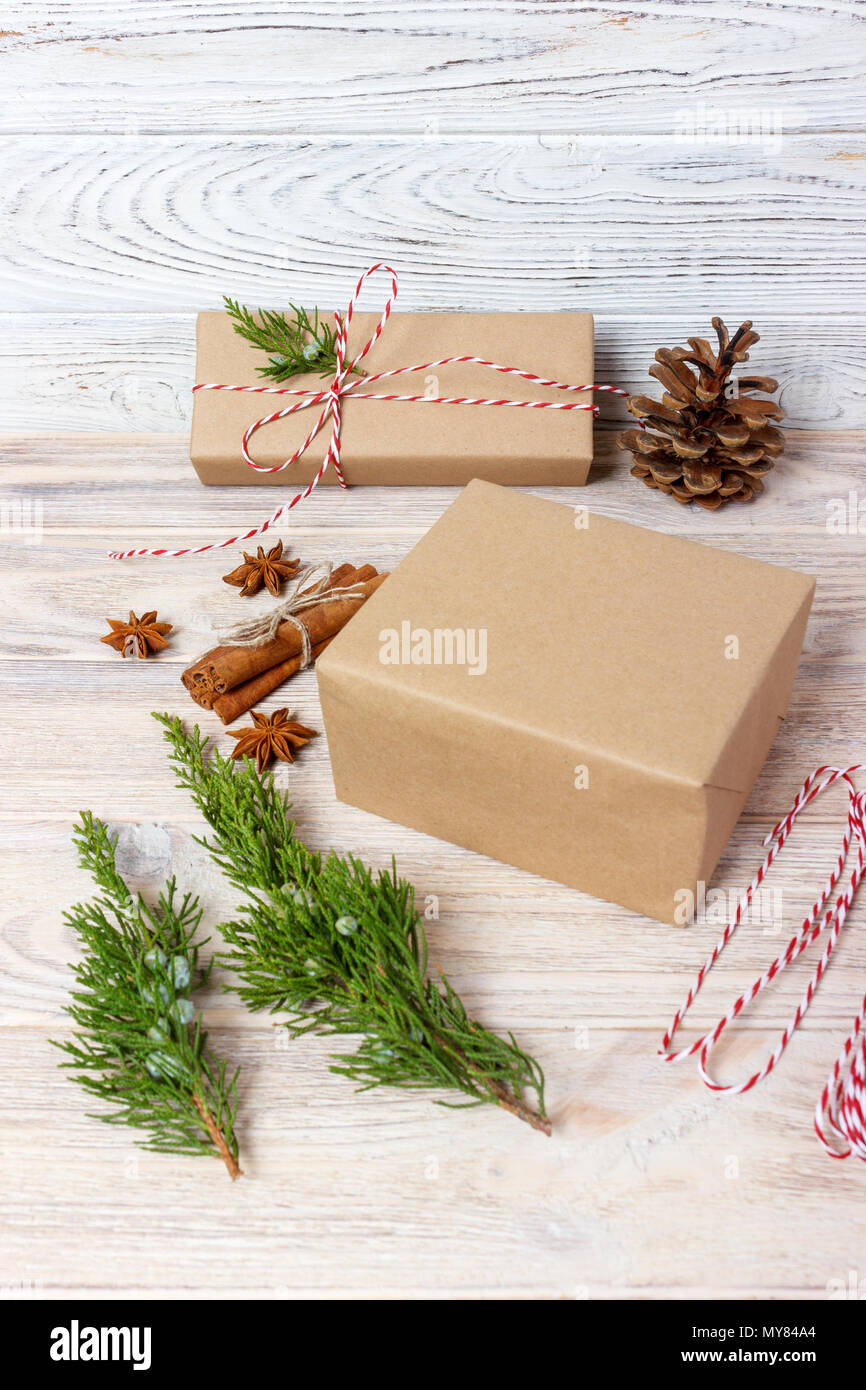 Creative hobby. Gift wrapping. Packaging modern christmas present boxes in stylish gray paper with satin red ribbon. Top view wood table with fir tree Stock Photo