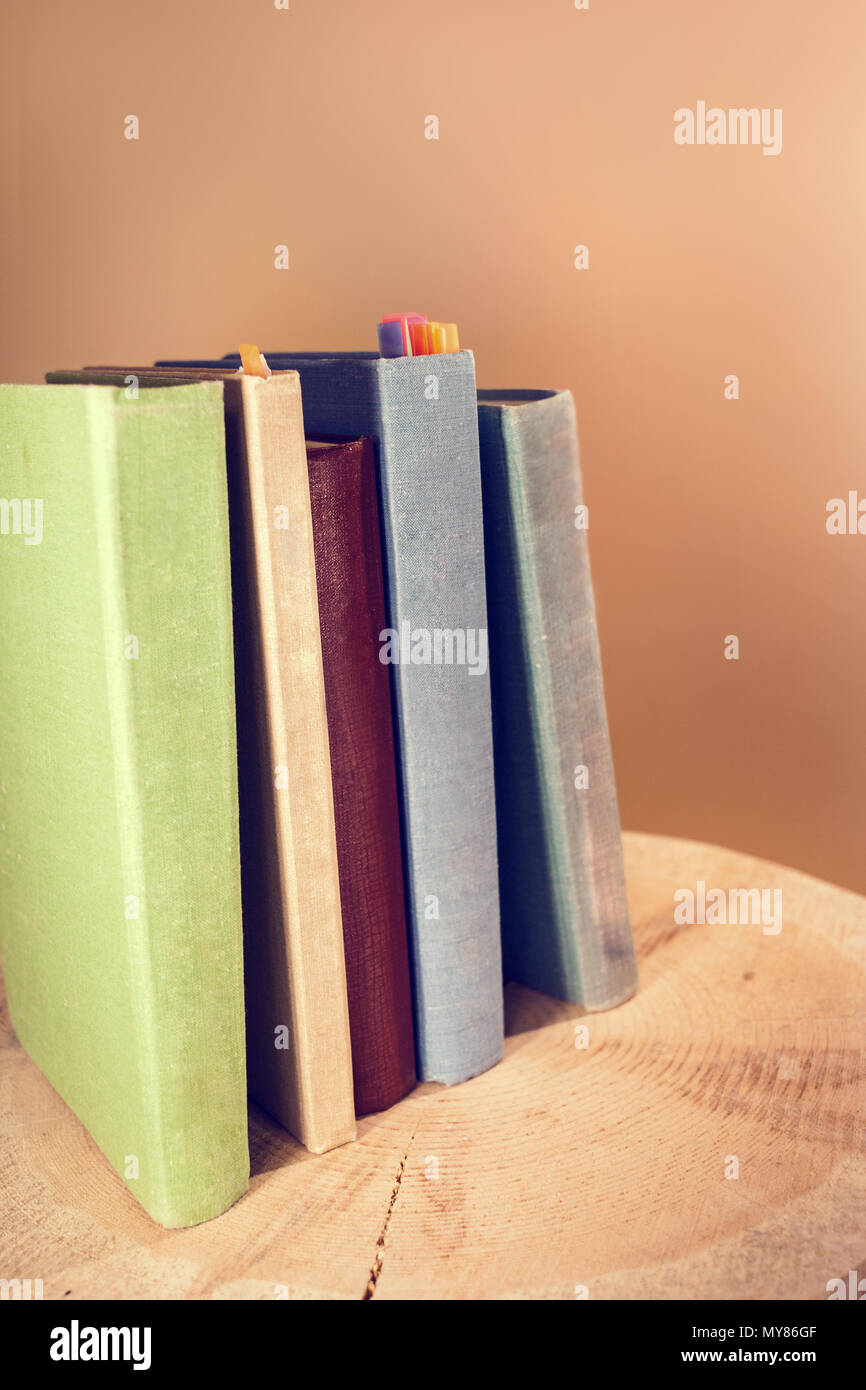 Retro toned image of vertical stack of old books on wooden saw cut