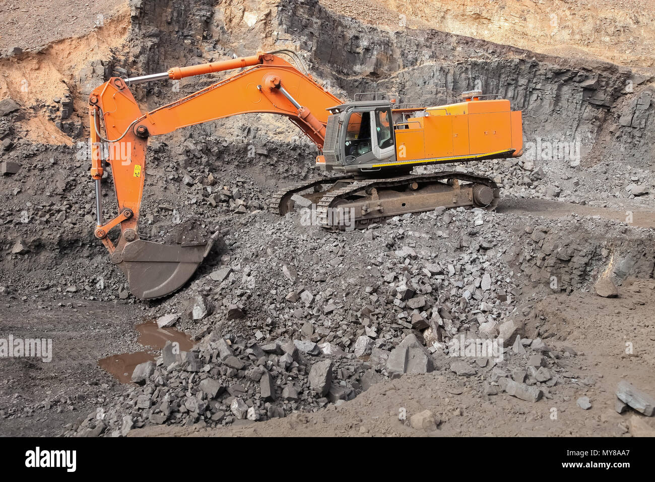 Excavator digging out ore rich rock and loading it onto rock dump