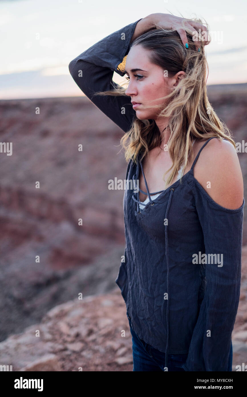 Young woman in remote setting, looking at view, holding hair off face, Mexican Hat, Utah, USA Stock Photo