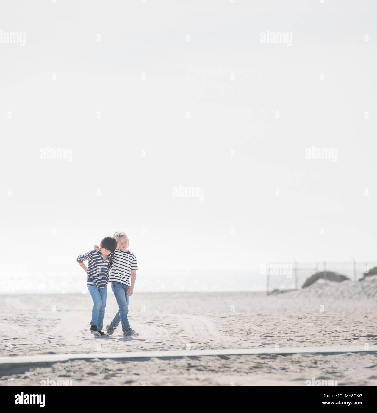 Boys walking on sandy beach Stock Photo