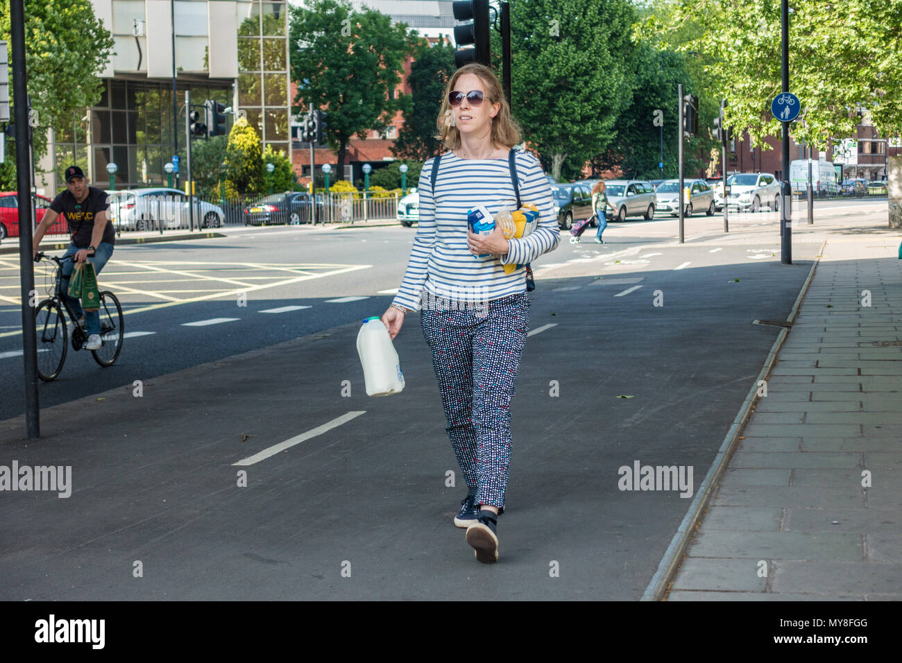 A woman walking through the streets carrying some recently purchased groceries. Stock Photo