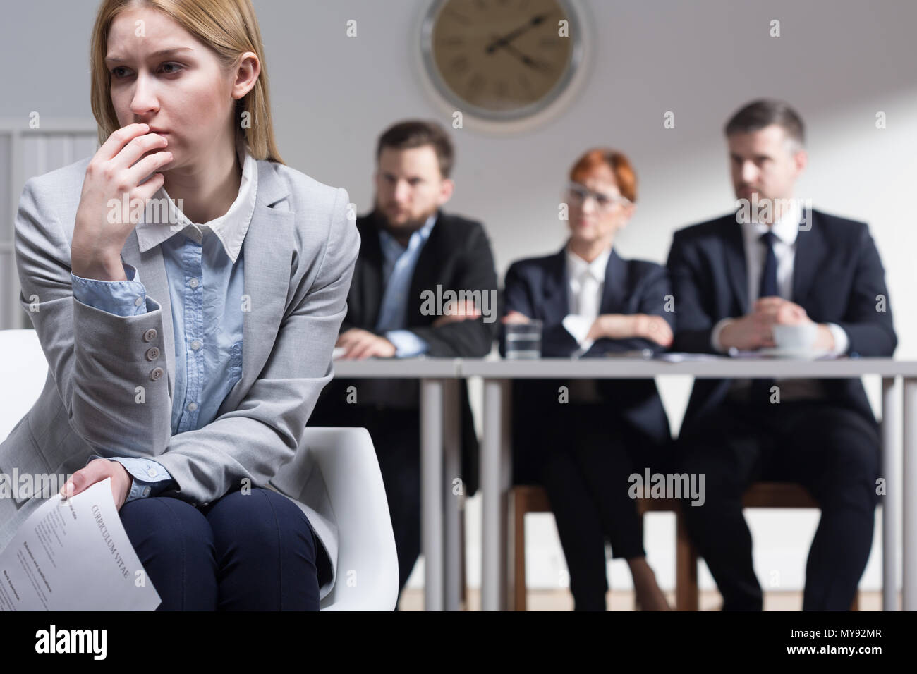 Sad woman holding CV and three businesspeople sitting beside table Stock Photo