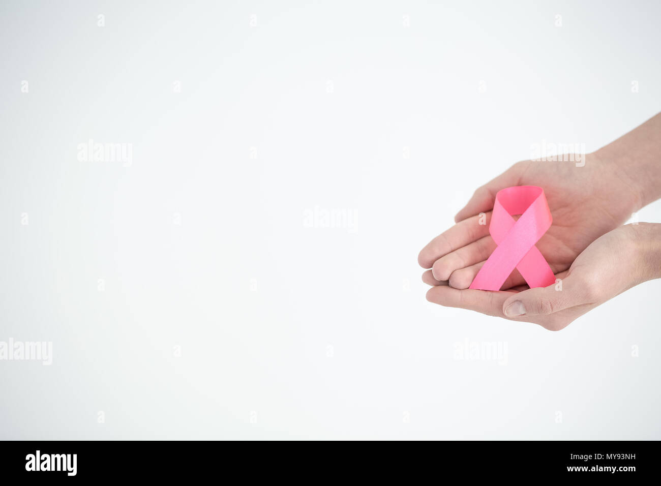 Hands holding pink ribbon on white background Stock Photo