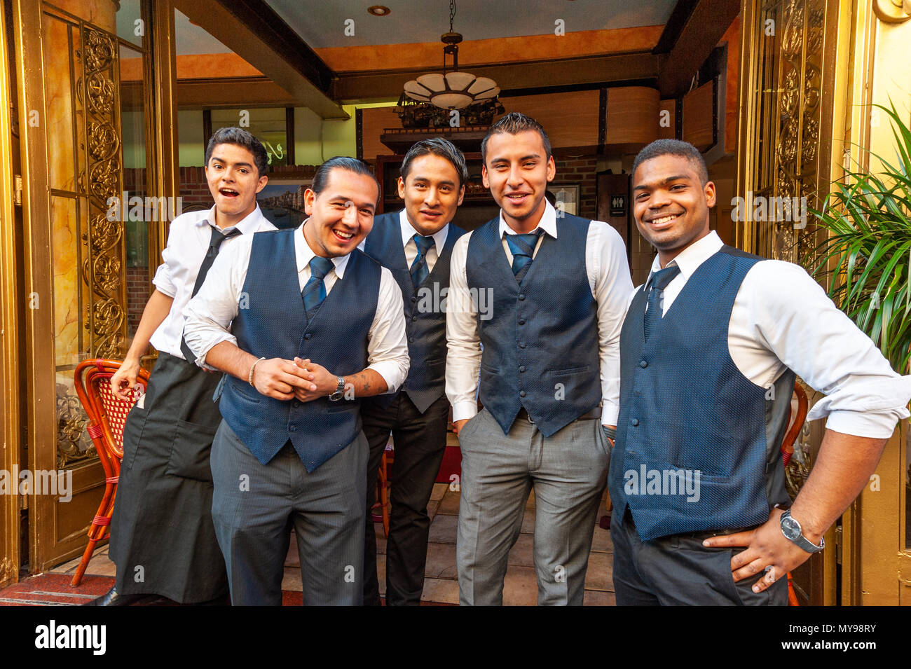 Group of Hispanic waiters posing for a photo outside restaurant on Mulberry Street in Little Italy, New York City, USA Stock Photo