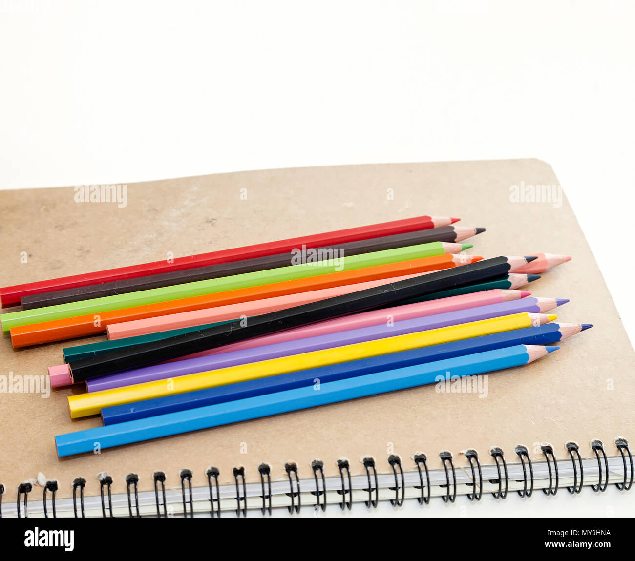 Colourful Pencils on a notebook . Isolated on a white background. Stock Image Stock Photo