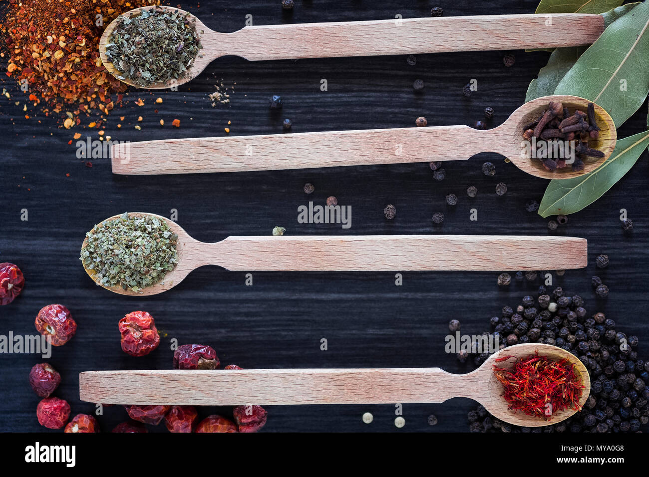 Four wooden spoons with various spices on dark wooden background Stock Photo