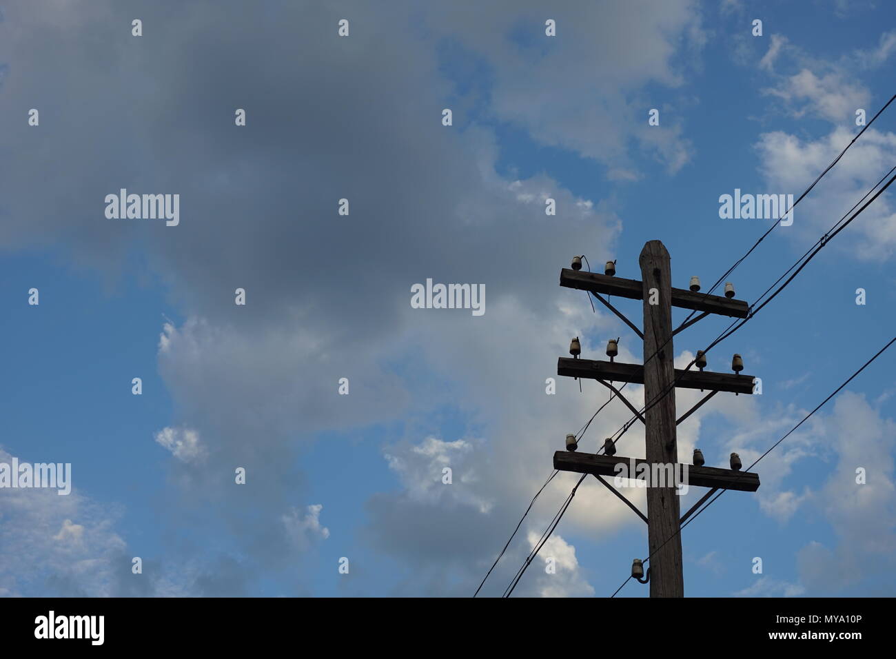 Old wooden electric pole on a blue cloudy sky background Stock Photo ...