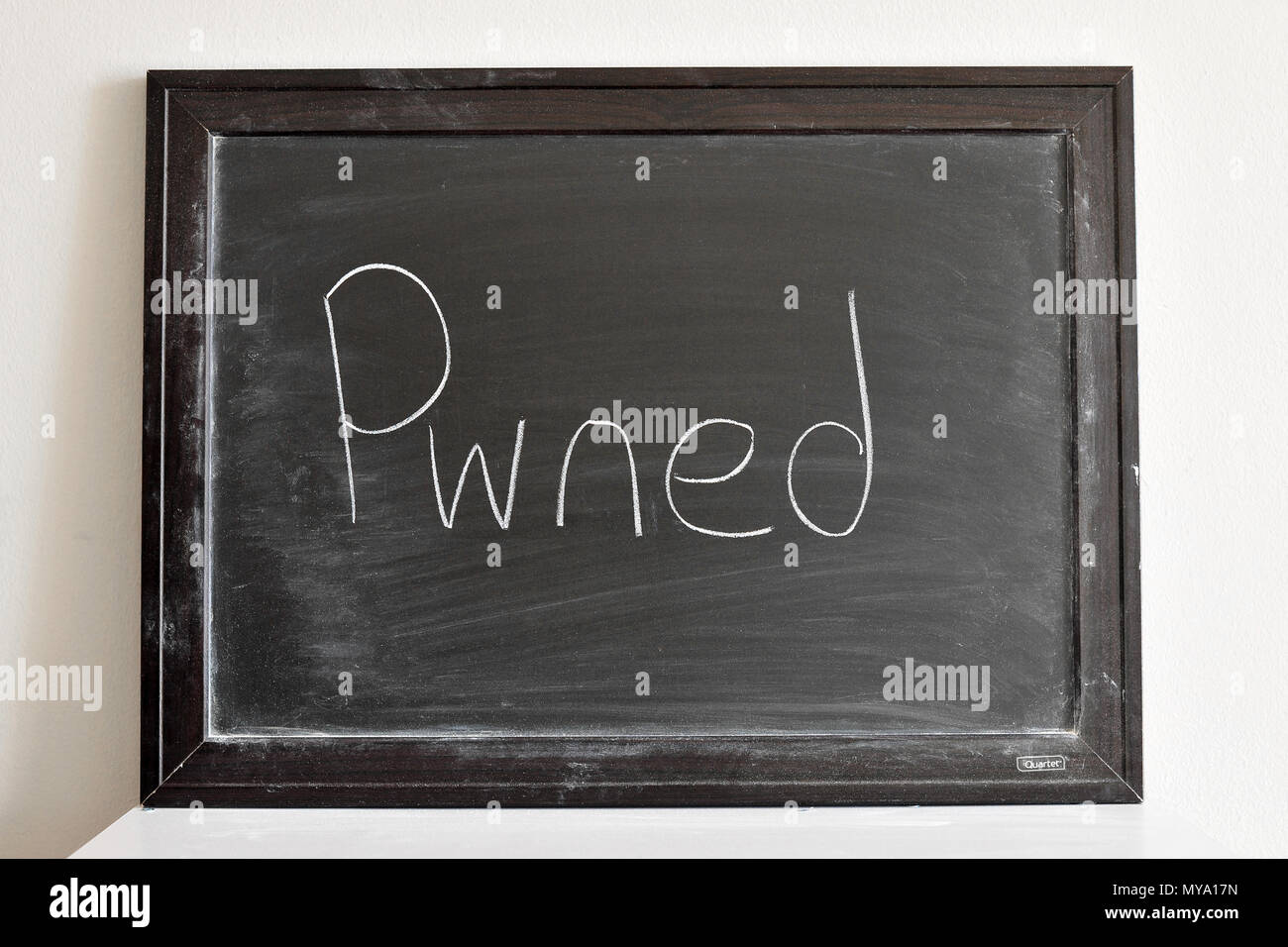 Pwned written in white chalk on a blackboard Stock Photo