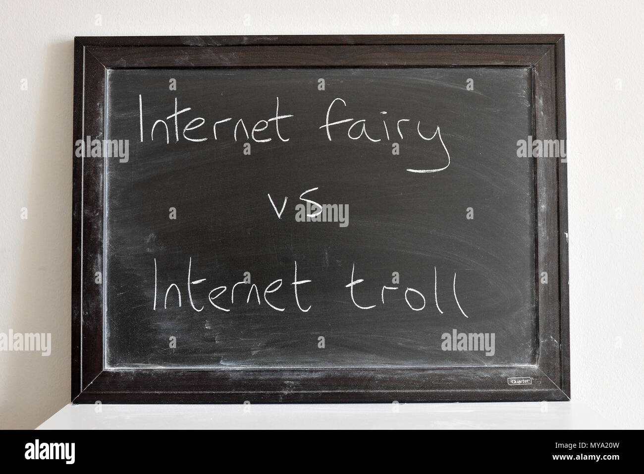 Internet fairy vs internet troll written in white chalk on a blackboard Stock Photo