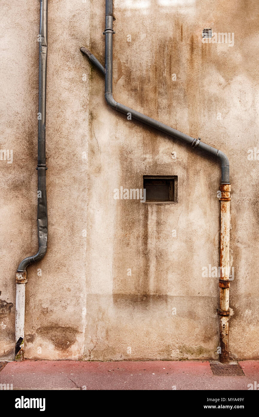 Two lead drainpipes snake down a wall in the town of Beaune at the center of the Burgundy region in France. Stock Photo