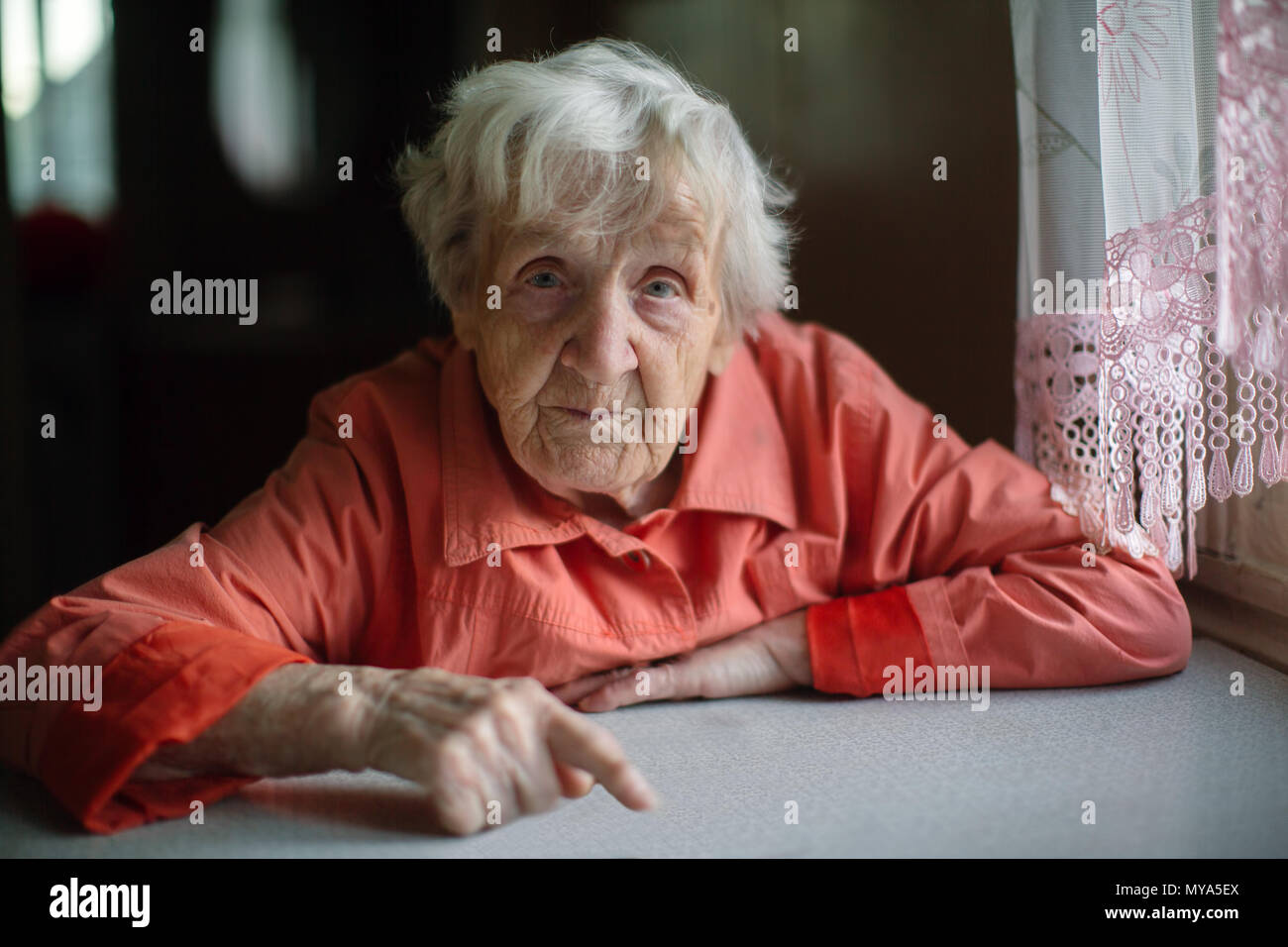 An elderly lady sitting near the window in the kitchen Stock Photo - Alamy