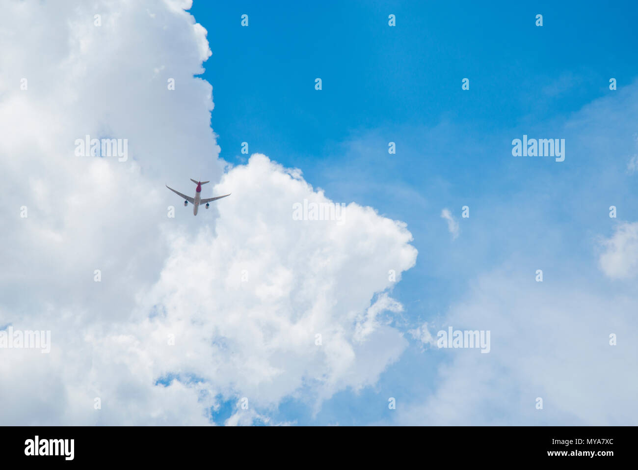 Plane flying across cloudy sky. Stock Photo