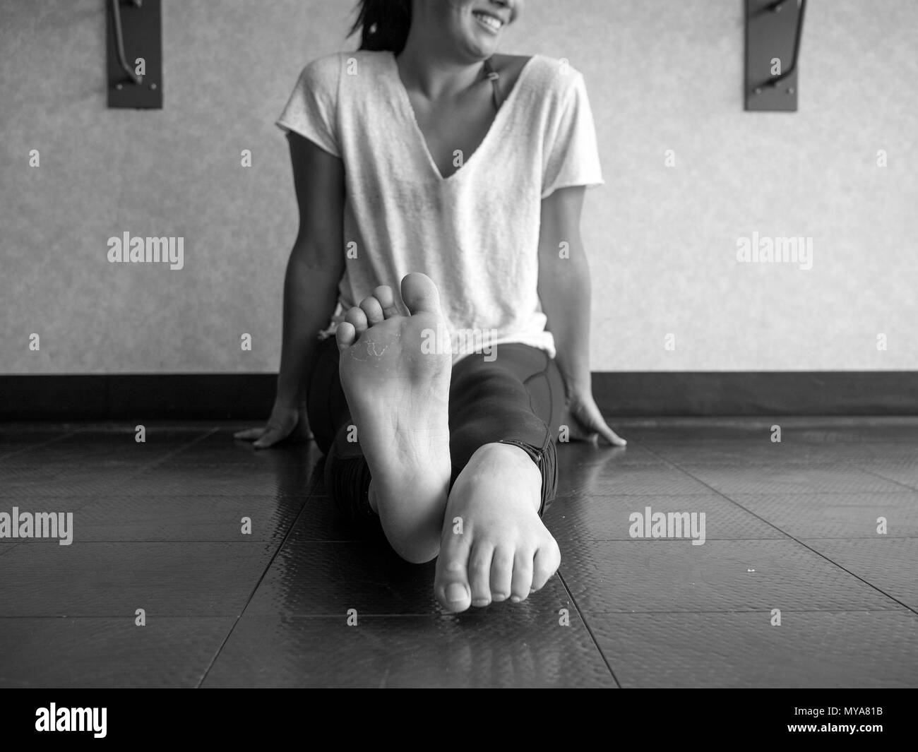 Black and white version of Smiling dancer warming up her feet with alternating pointing and flexing Stock Photo