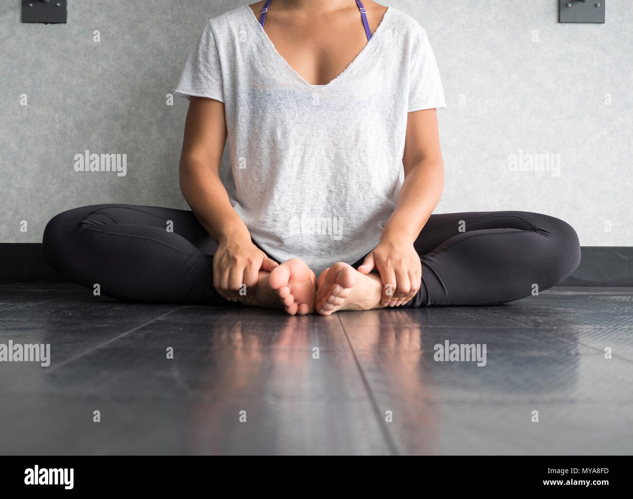 Female dancer sitting down in butterfly pose practicing yoga in the studio Stock Photo