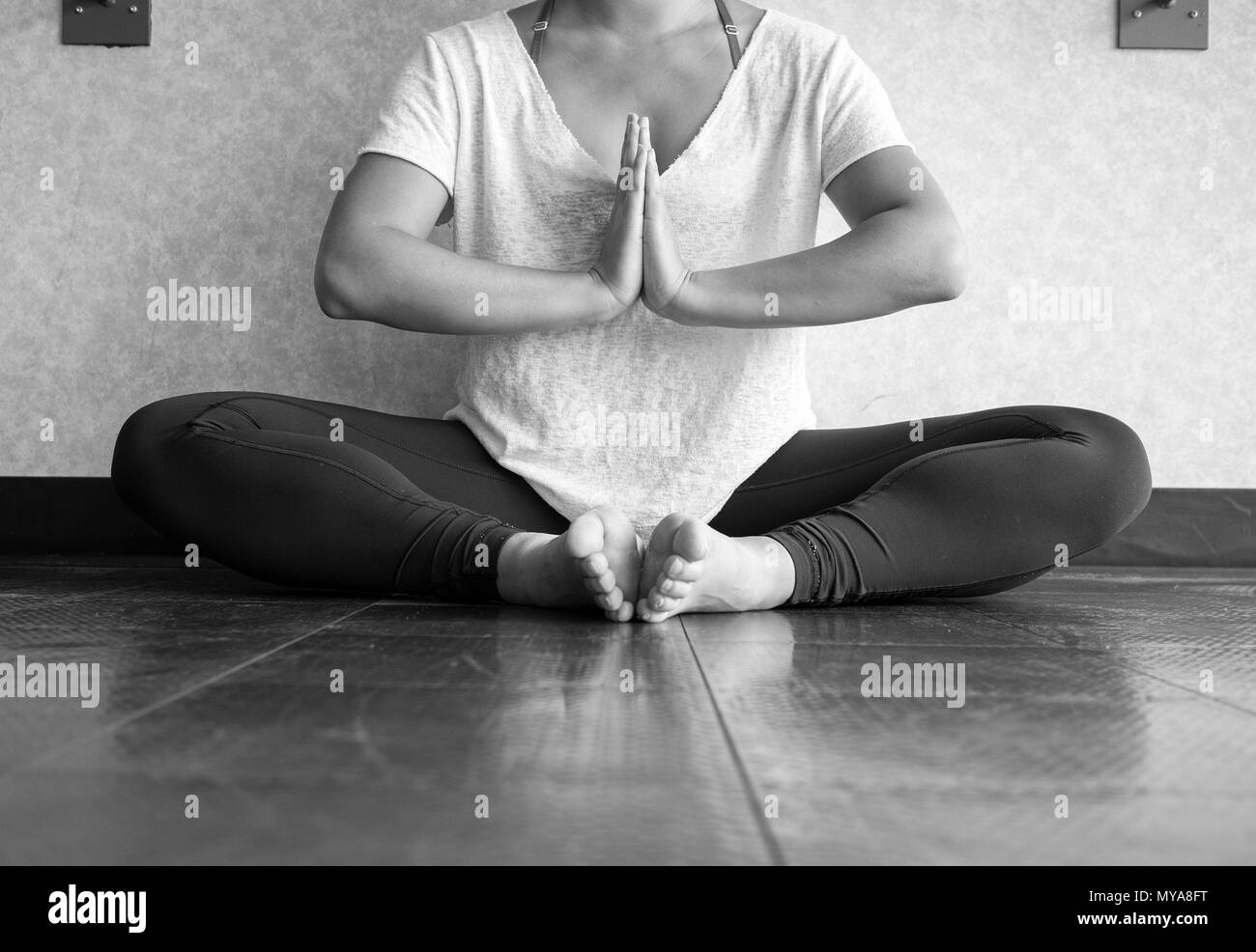 Black and white version of Young women practising yoga in butterfly position - Namaste Stock Photo