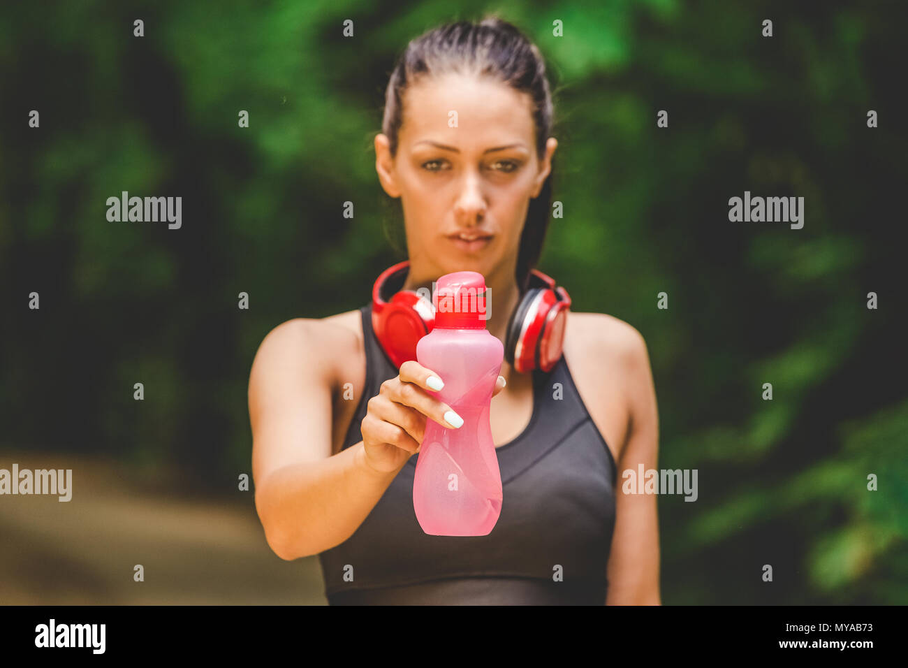 Portrait of female runner holding bottle of water in nature Stock Photo ...