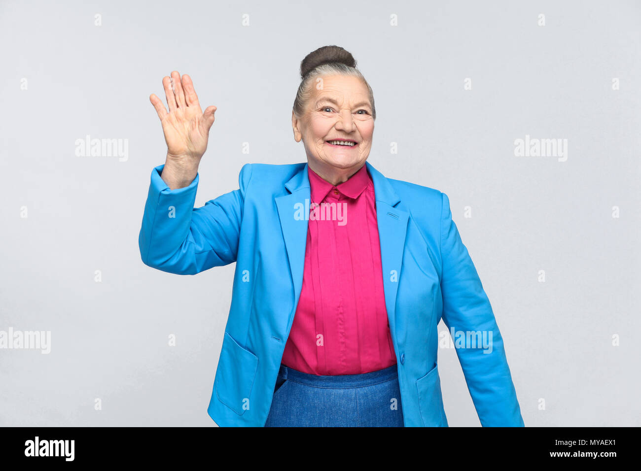 Happiness woman showing hi sign and toothy smiling. Emotion and feelings, Portrait of handsome grandmother with light blue suit standing with collecte Stock Photo