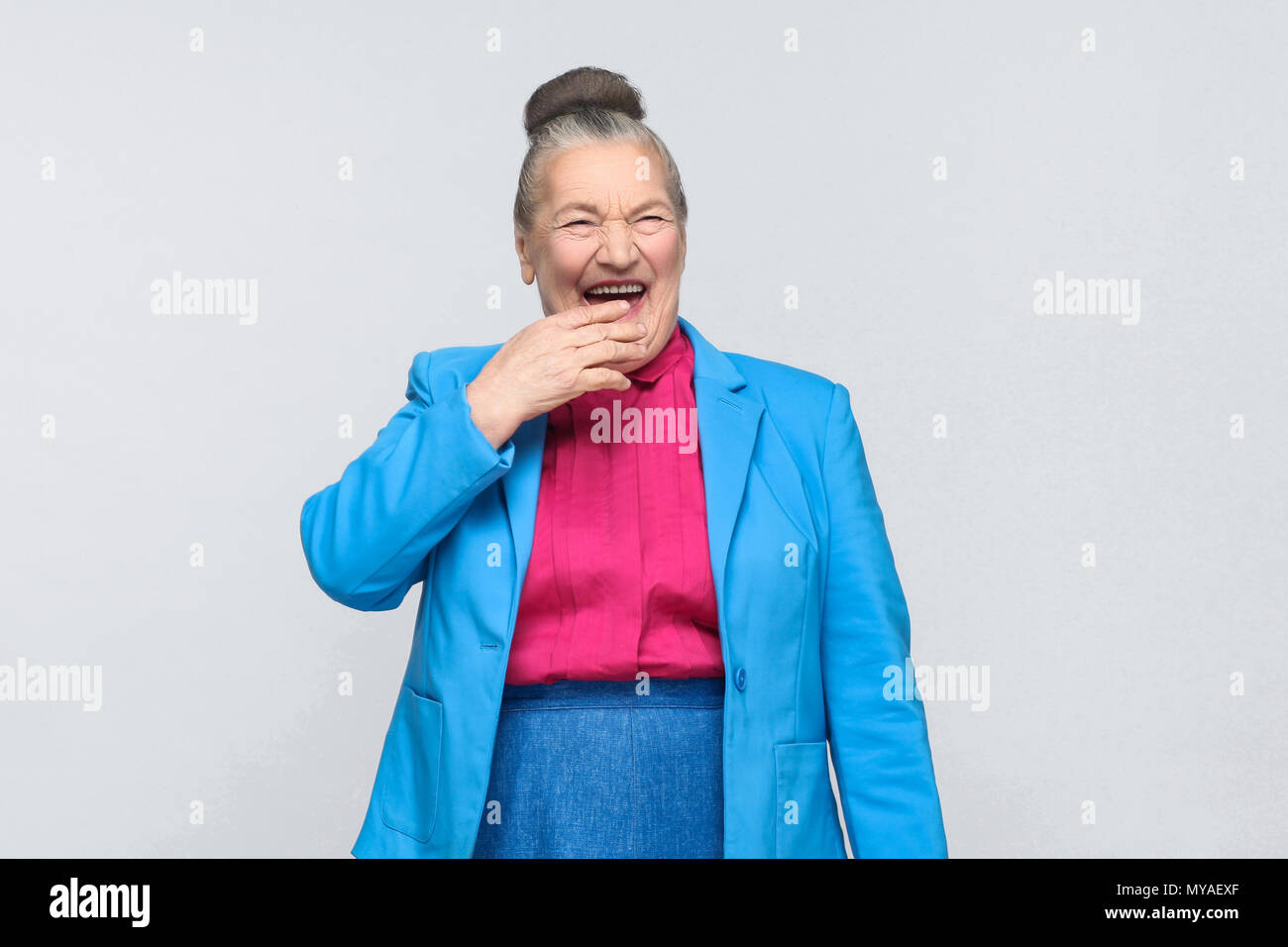 Funny aged woman laugh . Emotion and feelings. Portrait of handsome expressive grandmother with light blue suit and pink shirt standing with collected Stock Photo