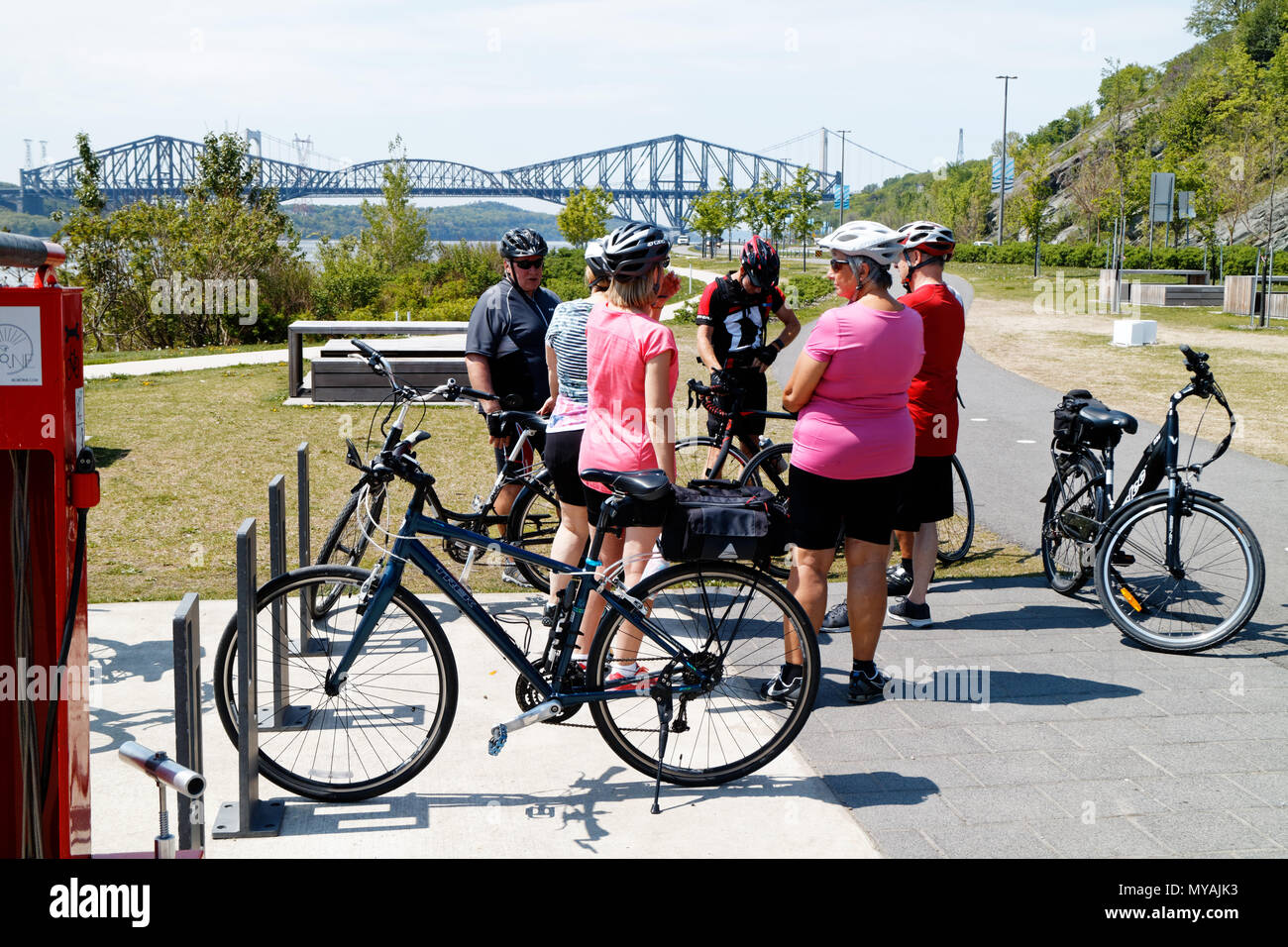 Cyclists on the Promenade Samuel de Champlain bike path in Quebec City, with the St Lawrence river at Pont du Quebec bridge beyond Stock Photo