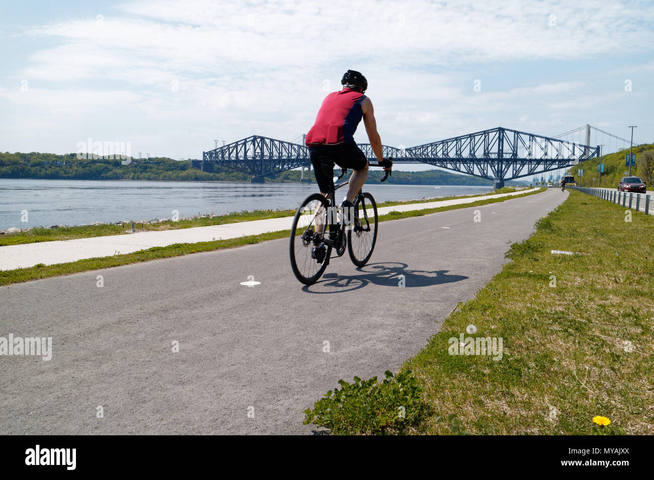 Cyclists on the Promenade Samuel de Champlain bike path in Quebec City, with the St Lawrence river at Pont du Quebec bridge beyond Stock Photo