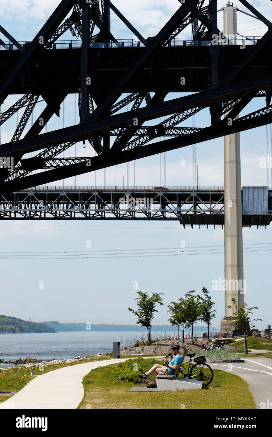 A cyclist relaxing on the Promenade Samual de Champlain cbike path in Quebec City, Canada with the Pont du Quebec overhead Stock Photo