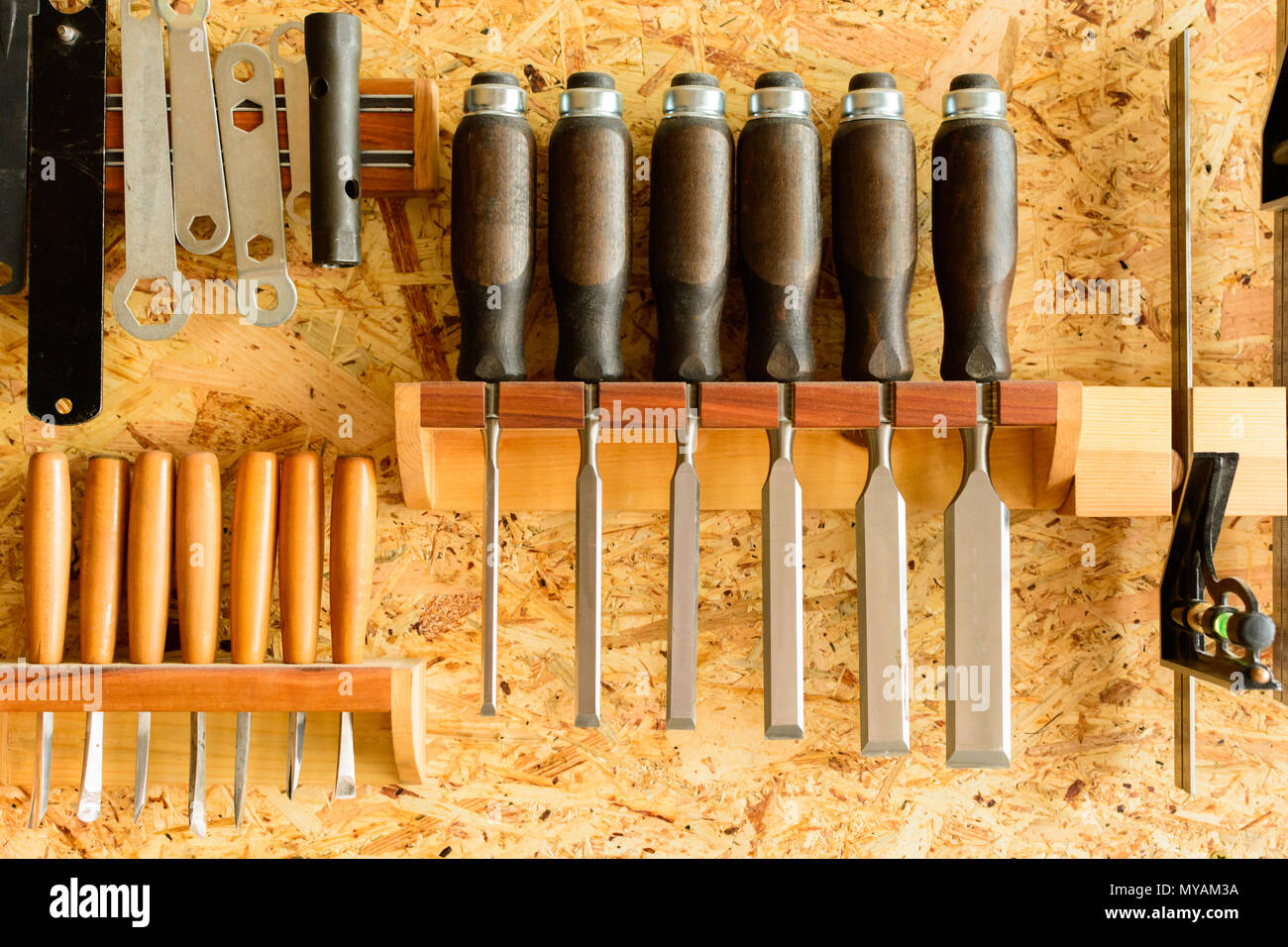 Carving tools hanging on the wall holder. The chisels aligned in the