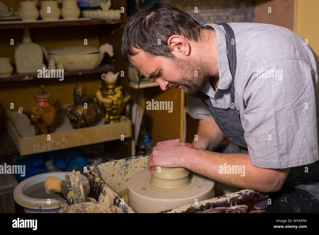 Professional male potter working with clay on potter's wheel in ...